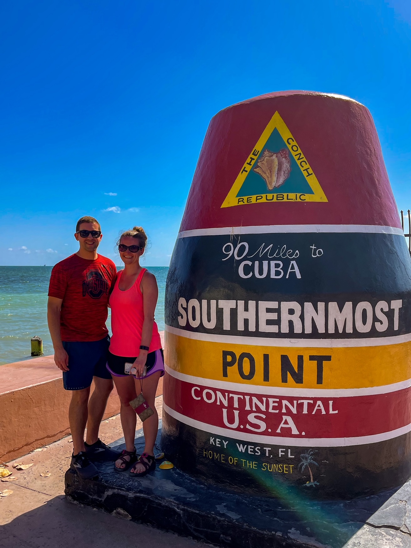 Two travelers standing by the Southernmost Point Sign in Key West, Florida.