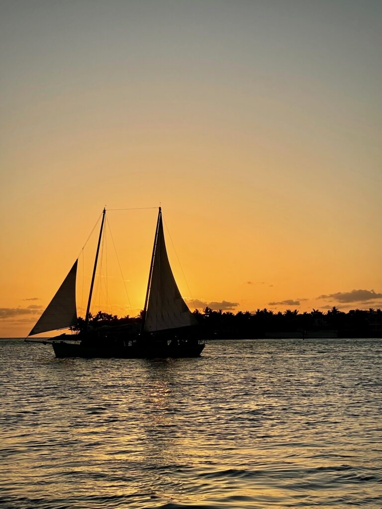 A sailboat sails past the sun near Mallory Square in Key West.