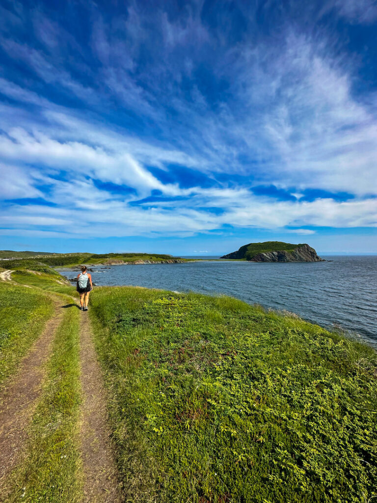A hiker along the Fox Island Trail with Fox Island in the distance.