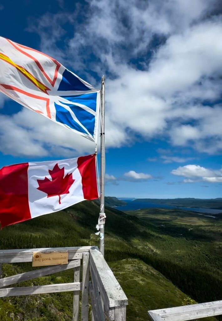 The Newfoundland and Labrador flag flying along with the Canadian flag at the Haypook summit of Alexander Murray Hiking Trail.