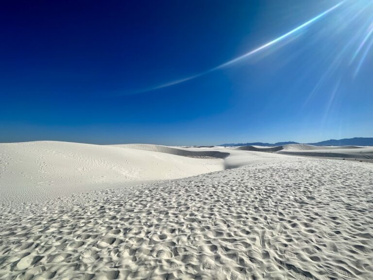 The white sands of the dunes stretch out under clear vibrant blue skies at White Sands National Park, New Mexico.