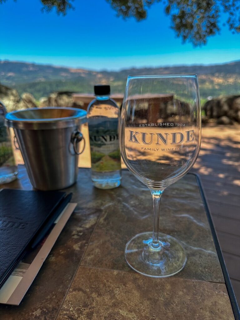 A Kunde Family Winery glass in the foreground with expansive views in the background.