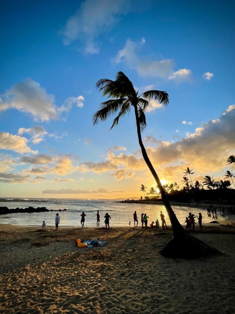 A crowd gathers on Poipu Beach to watch the sunset.