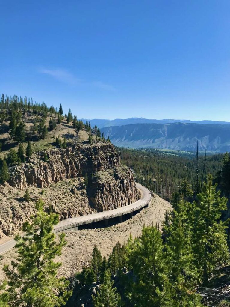 A road curving around a mountain below the Bunsen Peak Trail with Mammoth in the distance.