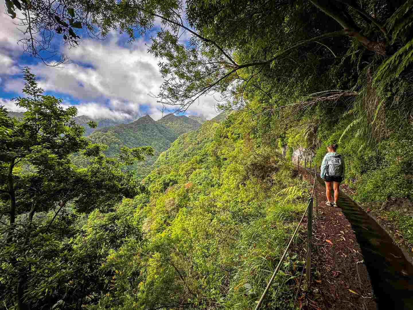 A hiker stands at a mountain overlook on the PR18 - Levada do Rei hike in Madeira, Portugal.