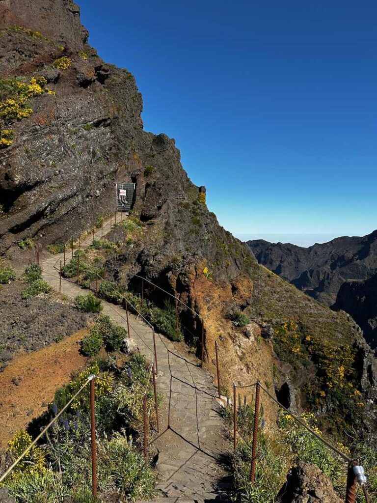 A zig-zagging trail leading to a trail closure that is blocked by a barrier.