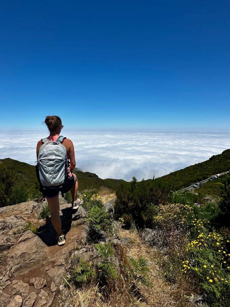 A hiker standing on the Pico Ruivo hike overlooking a view point of an ocean of clouds.