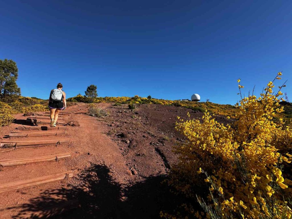 A hiker climbing a moderately steep trail to the summit of PR1 - Pico do Arieiro.