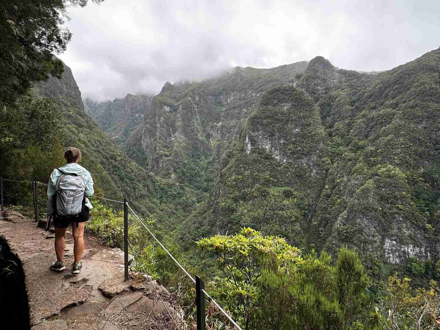 A hiker stands on the ledge of the Levada do Caldeirão Verde Hike.