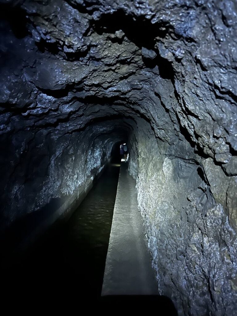 A hiker walking through the long, dark, tunnel in Madeira.