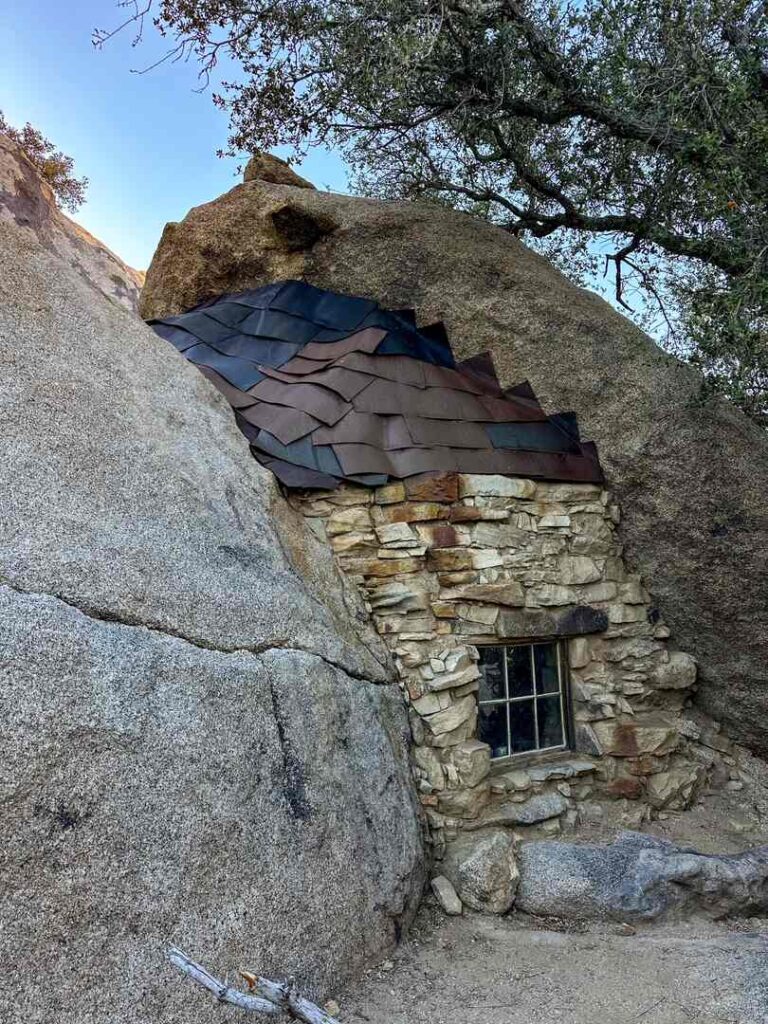 The reminants of a wall, window, and roof of a small miners cabin built into the stone.